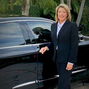 A woman standing next to a black cadillac.